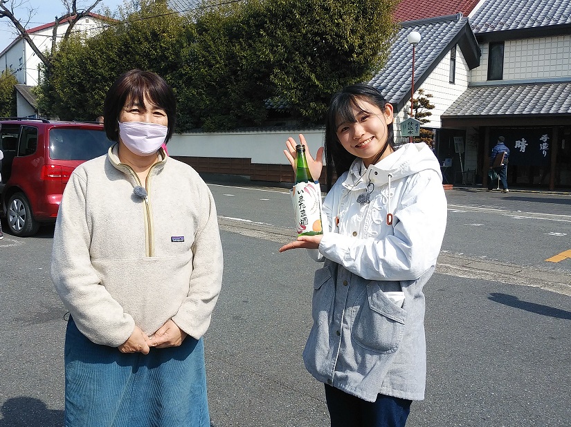 無農薬で米作りから酒造りを楽しむ会の事務局員と佐藤楓がいまたま酒を持った写真