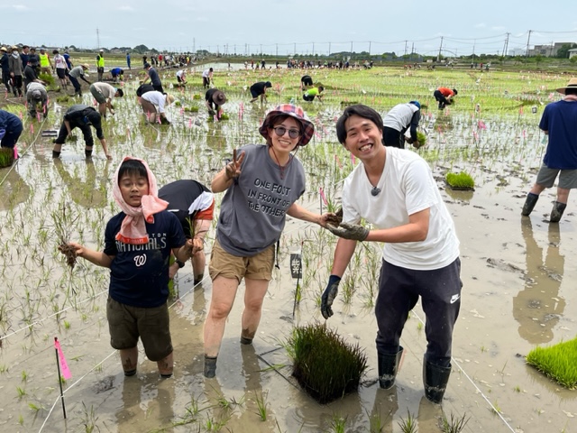 行田市田んぼアートの田植えを体験する参加者とカナイリポーターの写真