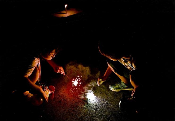 しゃがんで手持ち花火を見つめる二人の子供の写真