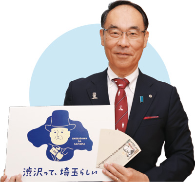 埼玉県知事 大野元裕 写真：「渋沢って、埼玉らしい」のロゴマークと新1万円札グッズを持って撮影