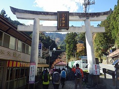 三峯山表参道の白い鳥居。数名の登山客の後ろ姿が写っている。