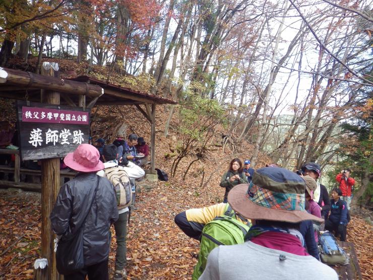 薬師堂跡という看板の前で休んでいる多くの登山客。