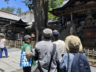 三峰神社の前でツアーガイドから解説を聞いている参加者。