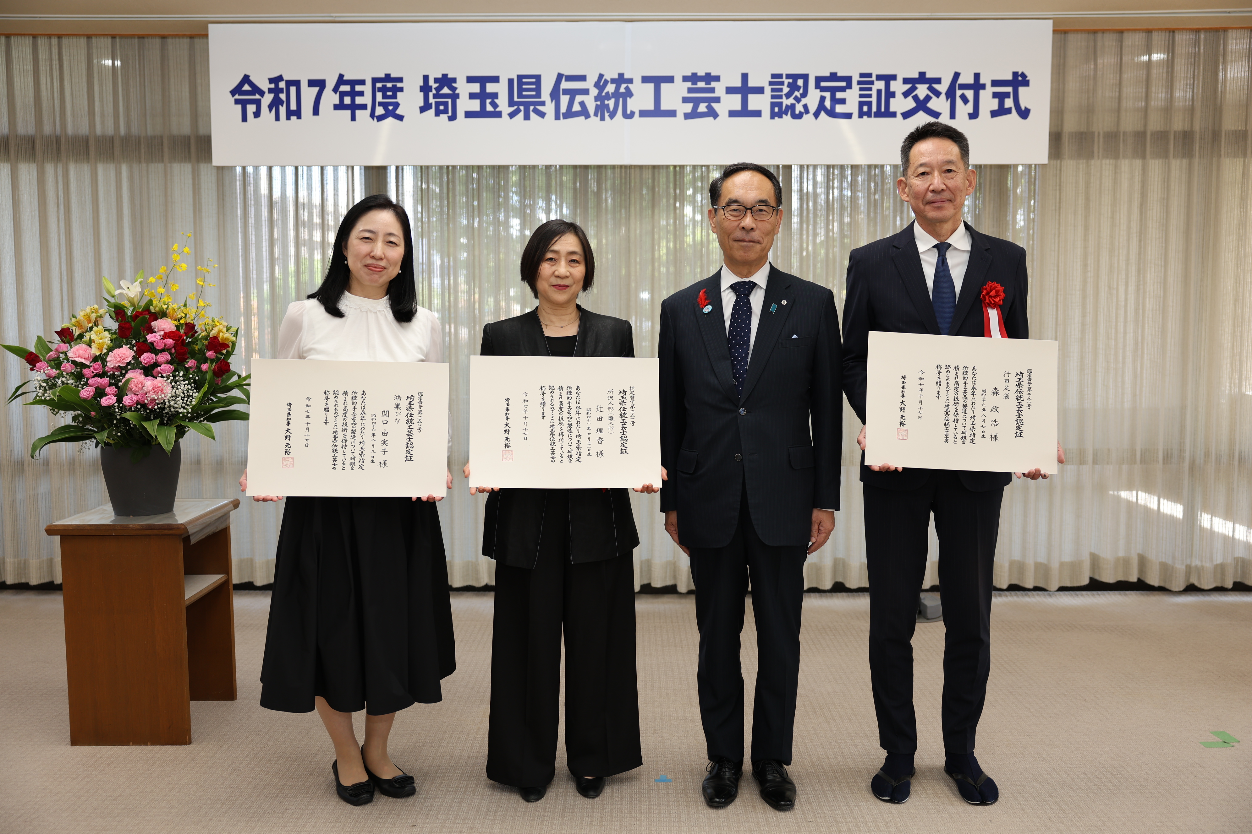 交付式で表彰者と記念写真を撮る知事の写真