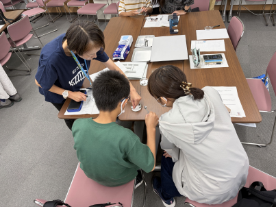 参加者の親子が、講師の職員からダンゴムシの体の構造について、説明を受けている様子の写真。